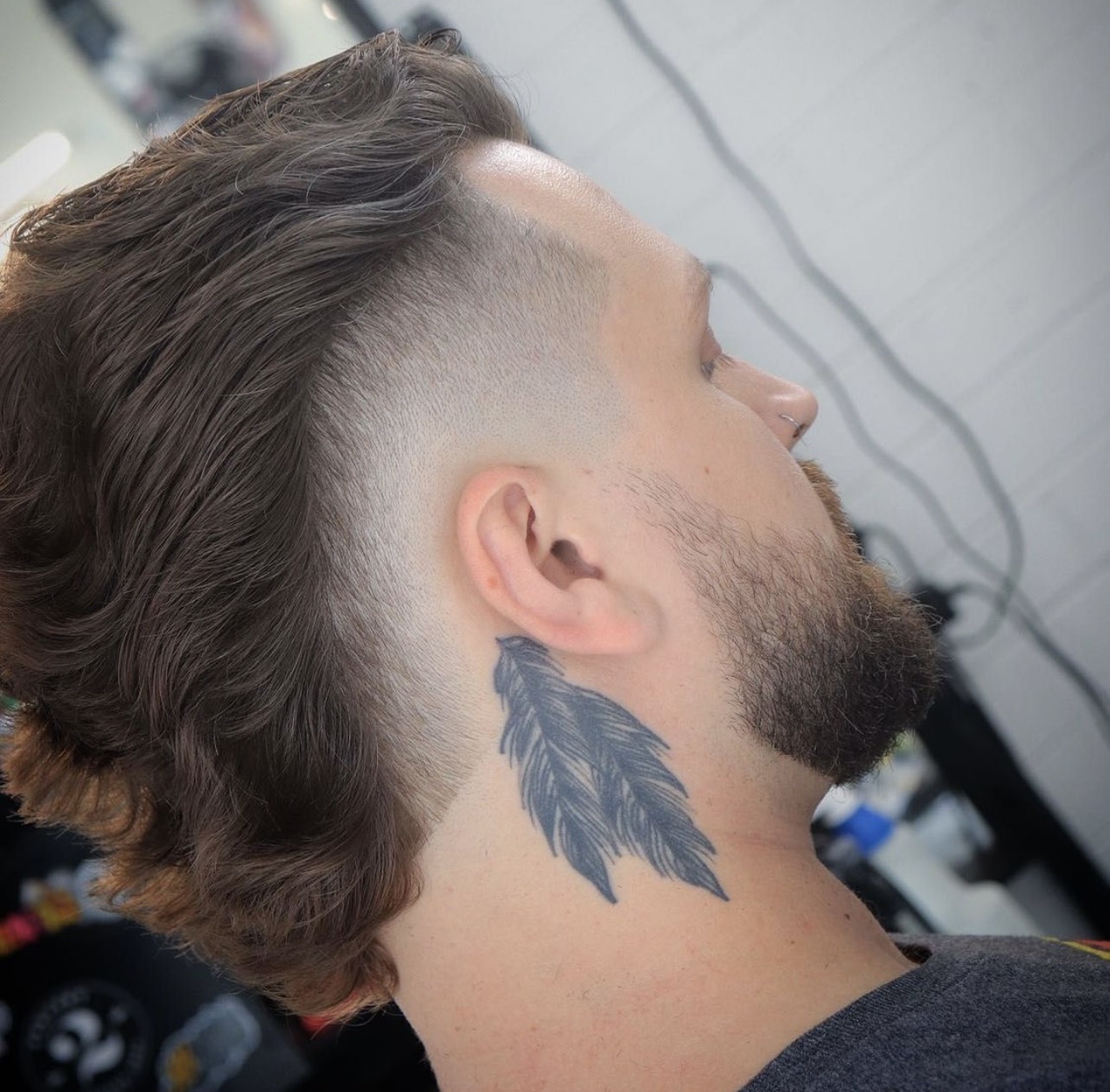 Man with a long wavy mullet-style cut, skin fade sides and a full beard