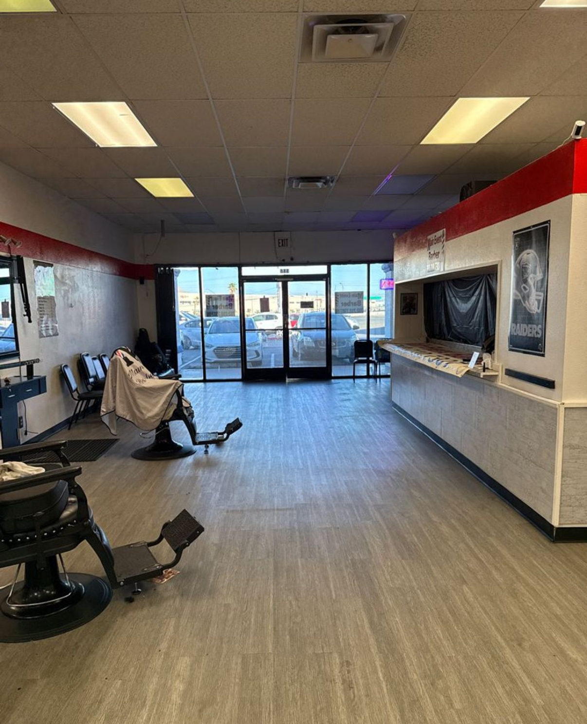 Barbershop interior with barber chairs, a reception counter and a Raiders poster