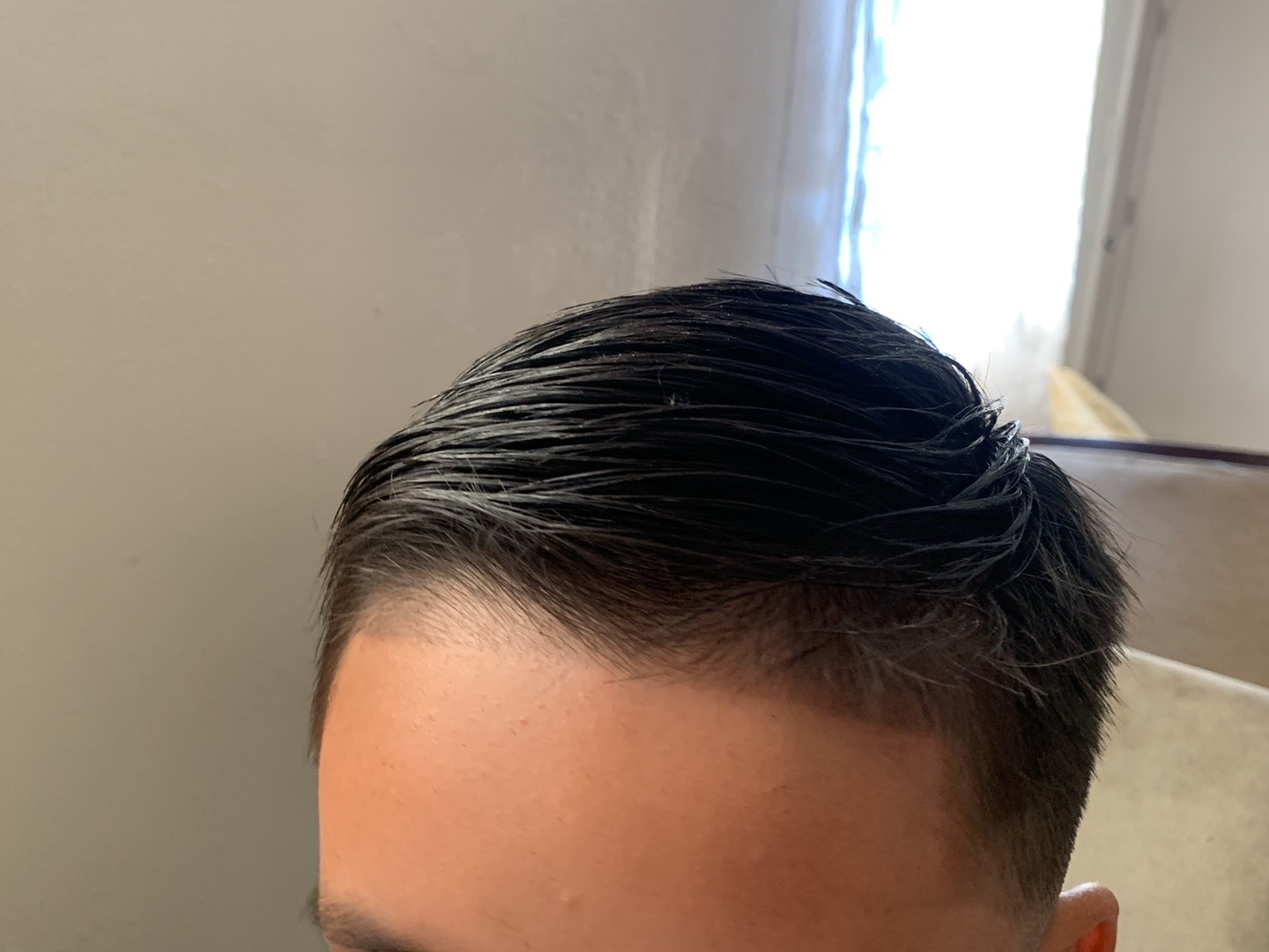 Top view of a man's slicked-back dark hairstyle with faded sides